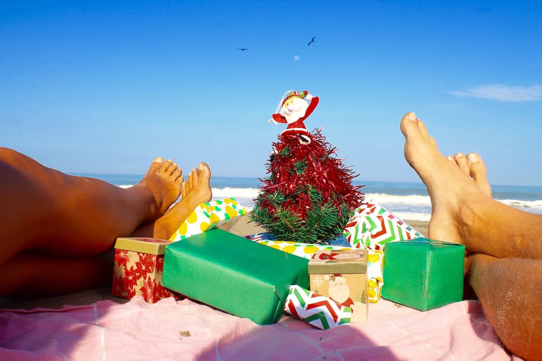 Van life gifts. Christmas tree with presents on the beach with two people's feet