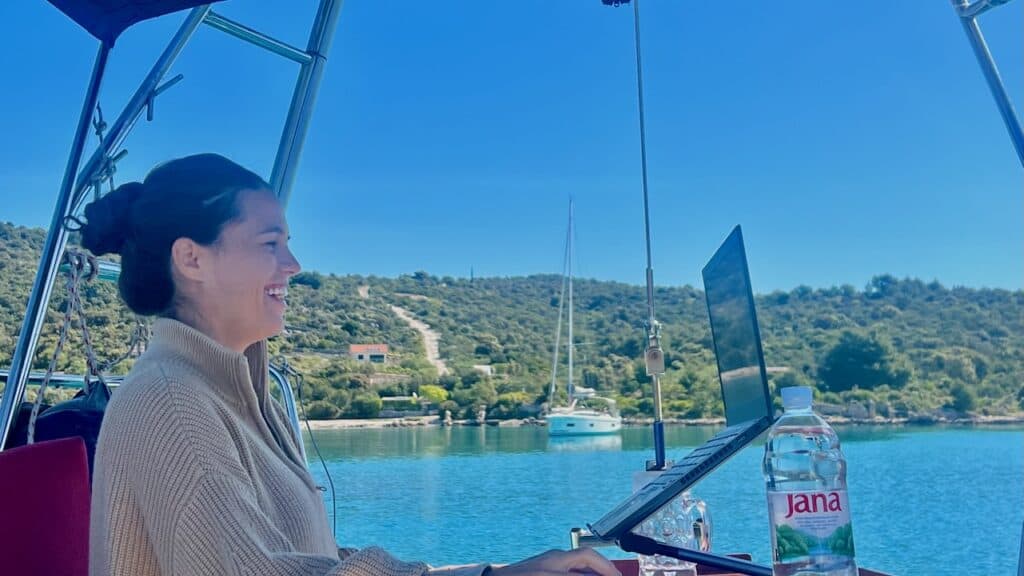 Staying Connected at Sea: Internet, Phones, Satellite & VPNs for Sailors 6 Kelli working from a sailboat day Staying Connected at Sea: Internet, Phones, Satellite & VPNs for Sailors