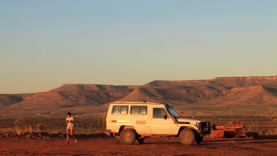 Woman and a car overlooking an escarpment at sunset. Gibb River Road