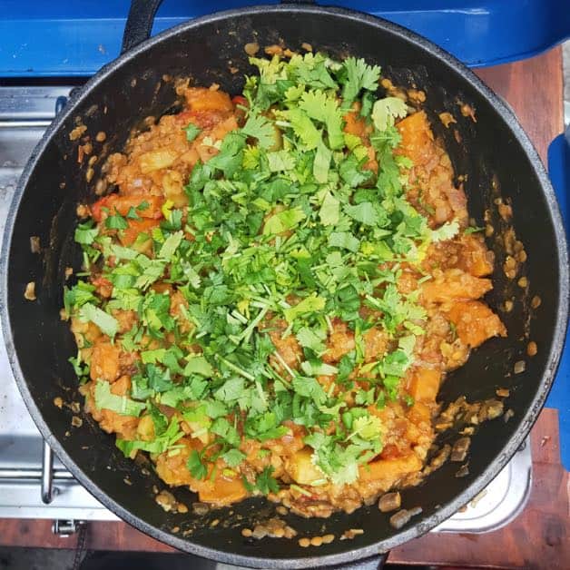 lentil and potato in a cast iron pot with coriander on top