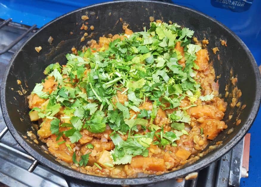 lentil and potato in a cast iron pot with coriander on top