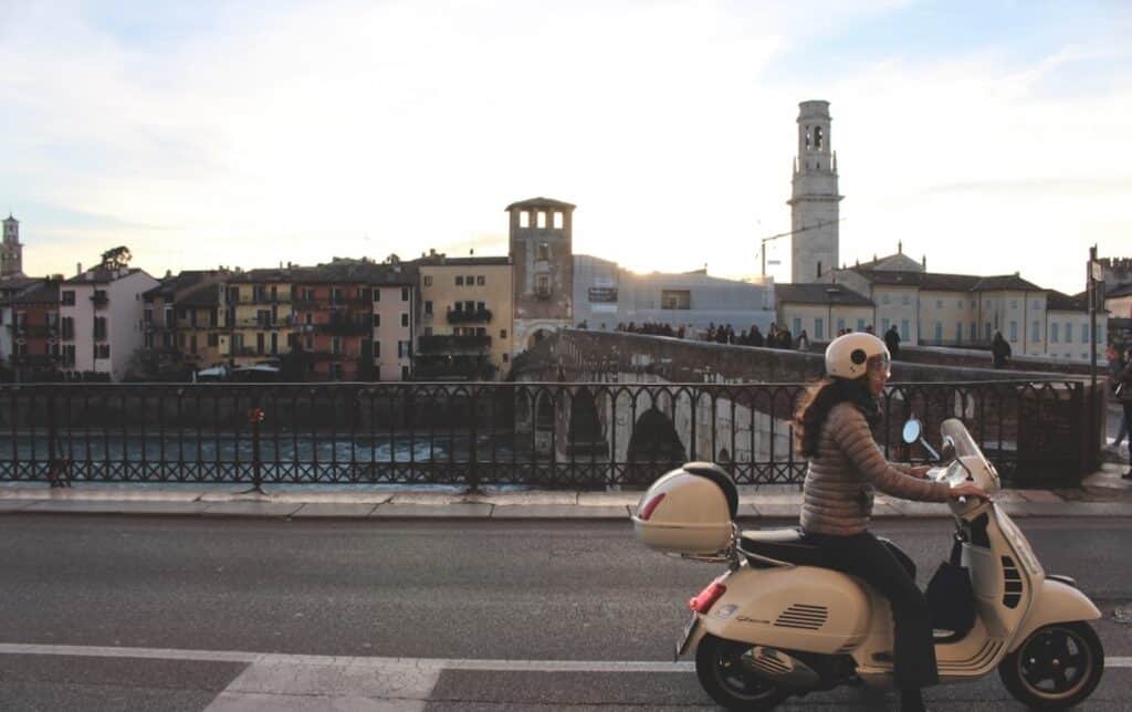 Girl on a moped racing through an Italian city at sunset 